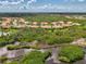 Community aerial view showcasing the landscape, ponds, tile roofs, and trees surrounding the houses at 13051 Creekside Ln, Port Charlotte, FL 33953