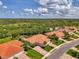 Aerial view overlooking the terracotta roofs of several homes and the lush green landscaping of the surrounding community at 13051 Creekside Ln, Port Charlotte, FL 33953
