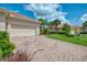 Long brick driveway leading to an attached garage with lush landscaping and blue skies at 13051 Creekside Ln, Port Charlotte, FL 33953