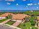Front exterior shot displays lush landscaping, paved driveway, a two-car garage, and tile roof near the water at 13051 Creekside Ln, Port Charlotte, FL 33953