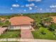 Exterior shot showcases house with lush landscaping, paved driveway, a two-car garage, and tile roof at 13051 Creekside Ln, Port Charlotte, FL 33953