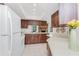 Bright kitchen with white appliances, wood cabinets, and convenient pass-through window to the cozy living room at 1337 Le Pera Rd, Englewood, FL 34223