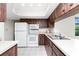 Functional kitchen featuring white appliances, wood-look cabinets, and ample counter space for meal preparation at 1337 Le Pera Rd, Englewood, FL 34223