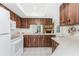 Well-lit kitchen featuring white appliances, wood-look cabinets, and pass-through to the living area with a fireplace at 1337 Le Pera Rd, Englewood, FL 34223