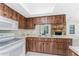 Efficient kitchen featuring white appliances, wood-look cabinets, and pass-through window to the adjacent living area at 1337 Le Pera Rd, Englewood, FL 34223