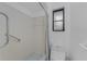 Shower stall with white and blue tiles, grab bar, and window at 1337 Le Pera Rd, Englewood, FL 34223