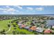 Scenic aerial view of a residential area featuring lush landscaping, golf course, and a tranquil lake at 13376 Golf Pointe Dr, Port Charlotte, FL 33953