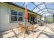 Outdoor seating area with a screened-in patio, umbrella, and views of the lush surroundings at 13376 Golf Pointe Dr, Port Charlotte, FL 33953