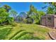 Well-maintained backyard with grassy lawn, screened pool area, and shed for storage at 1550 Bayshore Dr, Englewood, FL 34223