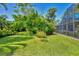 Large backyard with mature trees and landscaping, leading to screened pool area at 1550 Bayshore Dr, Englewood, FL 34223