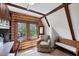 Bedroom featuring wood walls, exposed beams, a sitting chair, and a large window at 1550 Bayshore Dr, Englewood, FL 34223