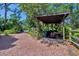 Brick driveway featuring wooden trellis, yard waste containers, and riding lawn mower at 1550 Bayshore Dr, Englewood, FL 34223