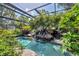 The screened pool area contains tropical landscaping and a rock waterfall feature at 1550 Bayshore Dr, Englewood, FL 34223