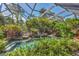 Gorgeous screened-in pool with lush landscaping, rock features, and clear water at 1550 Bayshore Dr, Englewood, FL 34223