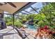 Lush landscaping surrounds the screened-in pool and patio area with beautiful rock waterfall feature at 1550 Bayshore Dr, Englewood, FL 34223