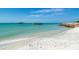 Picturesque beach scene with clear blue water, sandy shore, and old pier remains on a sunny day, with some rocks on the right at 15610 Staunton Cir, Port Charlotte, FL 33981