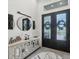 Beautiful entryway with decorative mirror, cabinet, and black double doors with glass panels at 15610 Staunton Cir, Port Charlotte, FL 33981