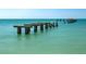 Scenic ocean view with remains of a pier jutting out into the calm, clear, turquoise water on a bright, sunny day at 15610 Staunton Cir, Port Charlotte, FL 33981