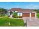Charming single Gathering home showcasing a three-car garage, lush landscaping, and a well manicured green lawn at 204 W Pine Valley Ln, Rotonda West, FL 33947