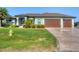 Beautiful single Gathering home featuring a lush lawn, colorful landscaping, and a three-car garage at 204 W Pine Valley Ln, Rotonda West, FL 33947