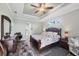 Main bedroom with tray ceiling and wood-look tile floors; the ensuite bathroom is accessible through an archway at 204 W Pine Valley Ln, Rotonda West, FL 33947