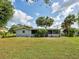 Well-maintained backyard with a partial view of a screened in porch, and mature trees at 21519 Fairway Ave, Port Charlotte, FL 33952