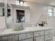 Well-lit bathroom features a marble-patterned vanity and a large mirror with updated lighting at 21519 Fairway Ave, Port Charlotte, FL 33952