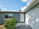 Close-up of the front entrance, showcasing a blue brick facade, stone walkway, and lush flower bushes at 21519 Fairway Ave, Port Charlotte, FL 33952