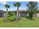 Lush backyard with tropical landscaping, including palm trees and a manicured lawn at 2592 Brassica Dr, North Port, FL 34289
