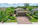 Charming home with a tile roof, two-car garage, brick driveway, and beautifully manicured landscaping at 2592 Brassica Dr, North Port, FL 34289