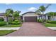 Charming single-story home with a brick driveway, manicured landscaping, and a two-car garage at 2592 Brassica Dr, North Port, FL 34289