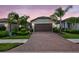 Charming single-story home with a brick driveway, manicured landscaping, and a two-car garage at twilight at 2592 Brassica Dr, North Port, FL 34289