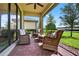 Relaxing screened patio with comfortable wicker furniture, ceiling fan, and brick flooring at 2592 Brassica Dr, North Port, FL 34289