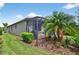 A cozy screened patio area is surrounded by lush landscaping, including palm trees and vibrant foliage at 2592 Brassica Dr, North Port, FL 34289