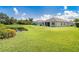 Expansive backyard with lush green grass, a serene pond, and home exterior at 267 Talquin Ct, Englewood, FL 34223