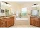 Bathroom featuring dual sinks, a garden tub, and tiled accents at 267 Talquin Ct, Englewood, FL 34223
