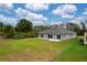 A well-maintained backyard with a gray house, lush green grass, and surrounding trees at 271 Antis Dr, Rotonda West, FL 33947