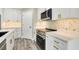 Kitchen with white cabinetry, gold hardware, tile backsplash, stainless steel appliances, and wood-style flooring at 271 Antis Dr, Rotonda West, FL 33947