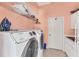 Modern laundry room with white washer and dryer and overhead shelving for storage at 285 Spaniards Rd, Placida, FL 33946