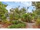 Lush tropical backyard with gravel pathways leading through palm trees and native plants at 365 Capstan Dr, Placida, FL 33946