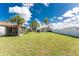 Spacious backyard featuring green grass, palm trees, and partial fencing at 4399 Mundella Cir, Port Charlotte, FL 33948
