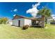 View of the house's backyard showing well-maintained grass, palm tree and enclosed patio at 4399 Mundella Cir, Port Charlotte, FL 33948