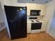 Bright kitchen with black appliances, white cabinetry, and wood-look laminate flooring at 4900 Hurley Ave, North Port, FL 34288