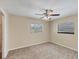 Bright bedroom boasts natural light from two windows, neutral colored walls and carpet, with a ceiling fan at 5412 Ulysses St, Port Charlotte, FL 33981