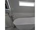 Freestanding white soaking tub with a stainless steel faucet and tiled wall in a modern bathroom at 608 Saint Judes Dr, Longboat Key, FL 34228