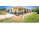 Side view of a yellow mobile home, featuring an attached covered area with decorative stone landscaping at 6293 Sparrow Ln, Englewood, FL 34224