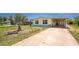 Charming yellow home featuring a well-manicured yard, large driveway, and a convenient covered parking area at 6293 Sparrow Ln, Englewood, FL 34224