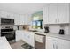 Bright kitchen features white cabinets, stainless steel appliances, and a window overlooking the yard at 6293 Sparrow Ln, Englewood, FL 34224