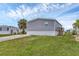 This gray home features a well-manicured lawn, a concrete driveway, and tropical landscaping at 7337 Desant Ln, Port Charlotte, FL 33981