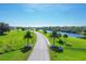 Scenic entrance to a neighborhood with a paved road, mature trees, and lush green spaces at 7337 Desant Ln, Port Charlotte, FL 33981